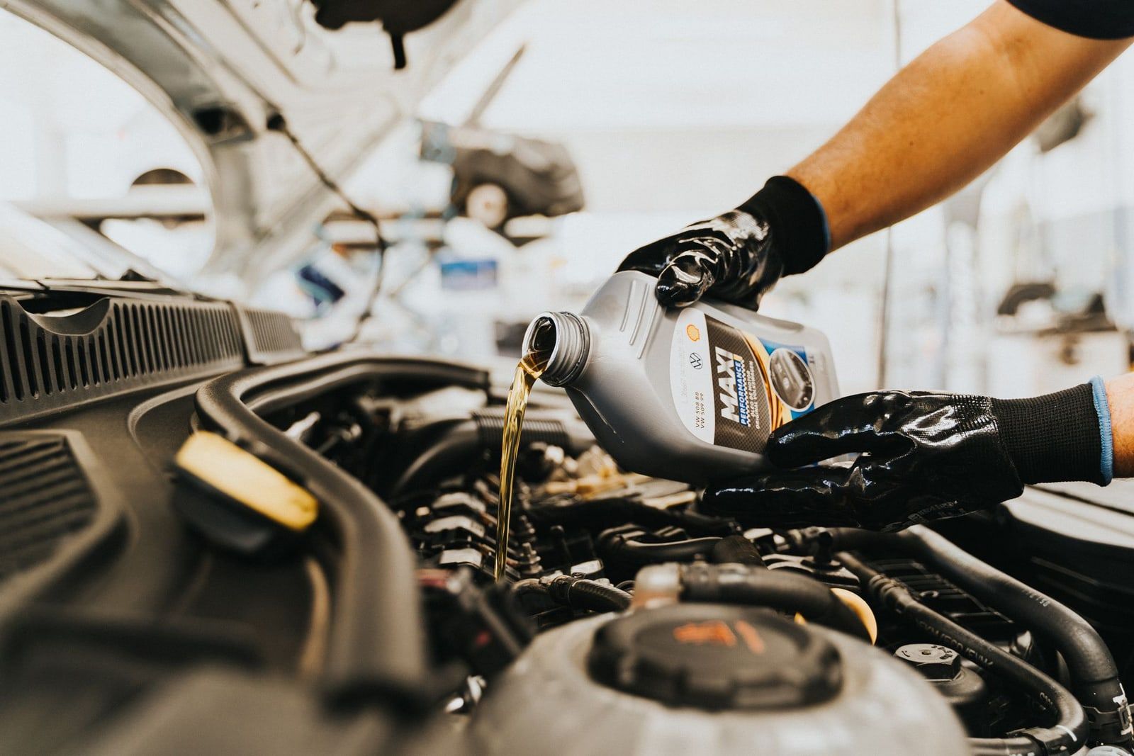 Mecánico echando aceite nuevo en el motor de un coche